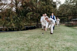 People running playfully across a grassy lawn near cypress trees. Wedding in Deville, La