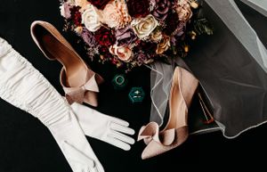 Wedding details flatlay with pink heels, bouquet, rings and white fabric on dark background.
Wedding Venue
