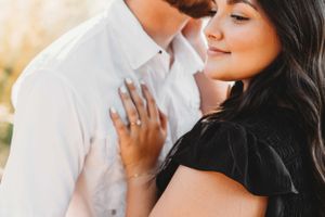 Intimate close-up photo of an engagement moment with a couple dressed in black and white in golden sunlight.