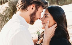 Romantic couple sharing intimate moment outdoors with gentle touching and soft lighting.