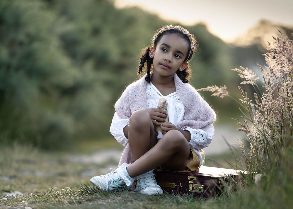 A serene outdoor portrait in a natural setting with golden light and wild grasses.