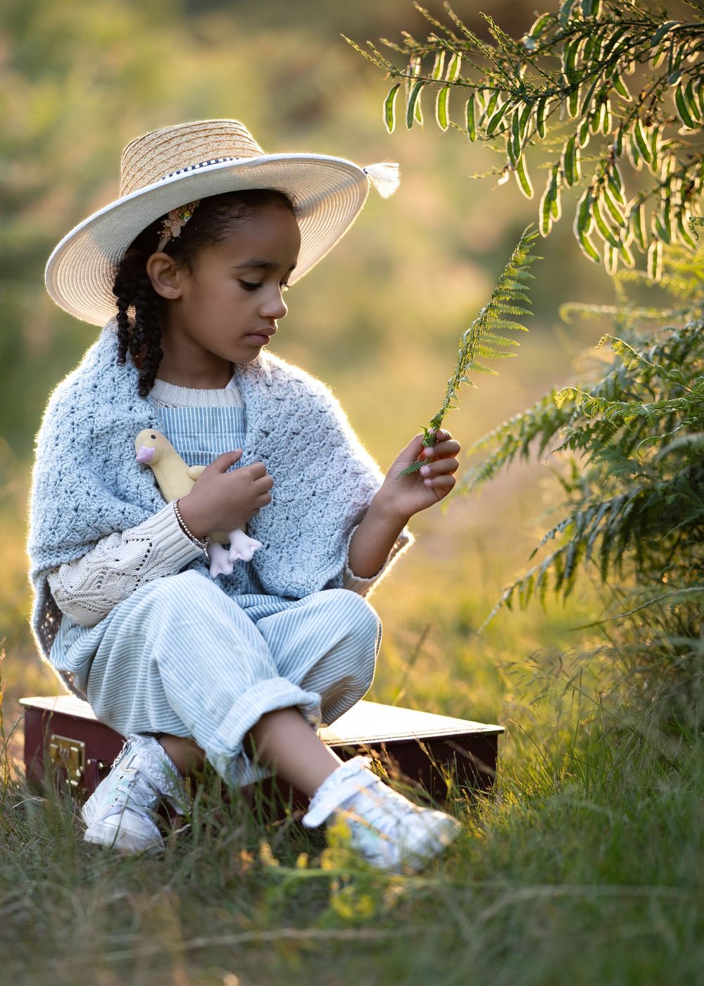 A gentle moment captured of someone in overalls and a hat examining pine branches.