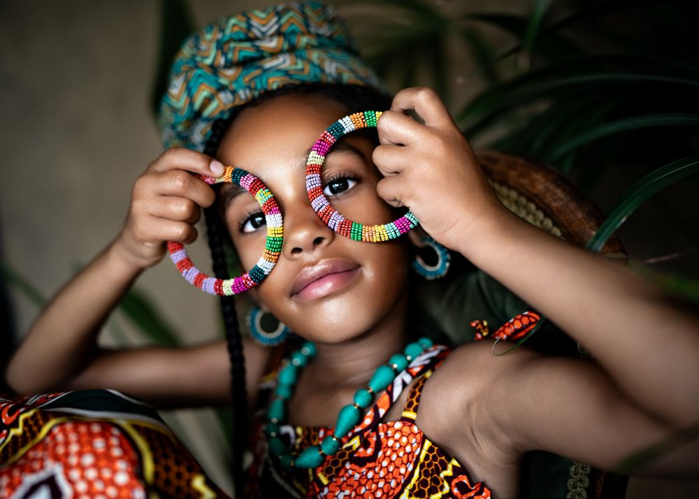 A creative portrait featuring colorful beaded bracelets and traditional African prints.