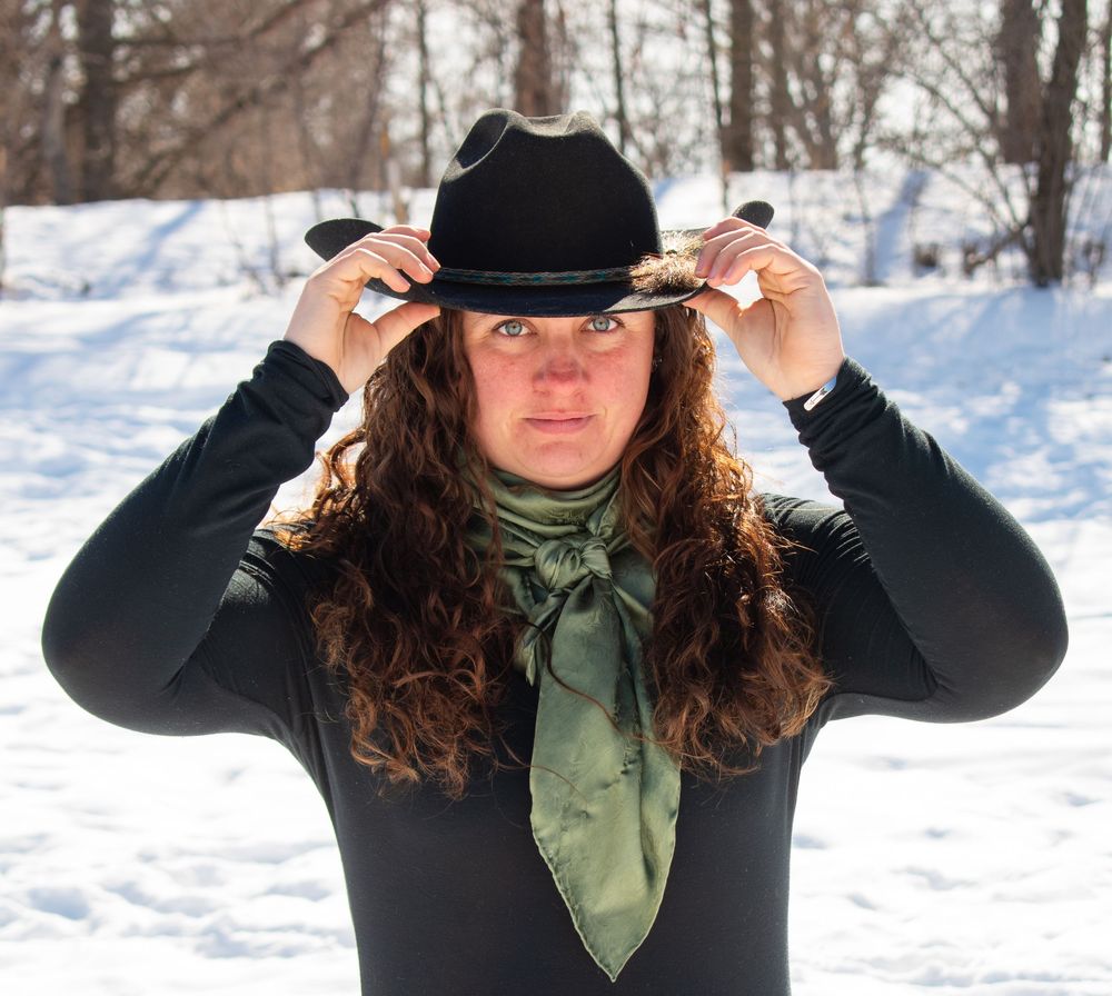 Cowgirl standing with hands on hat in a Wisconsin winter scene