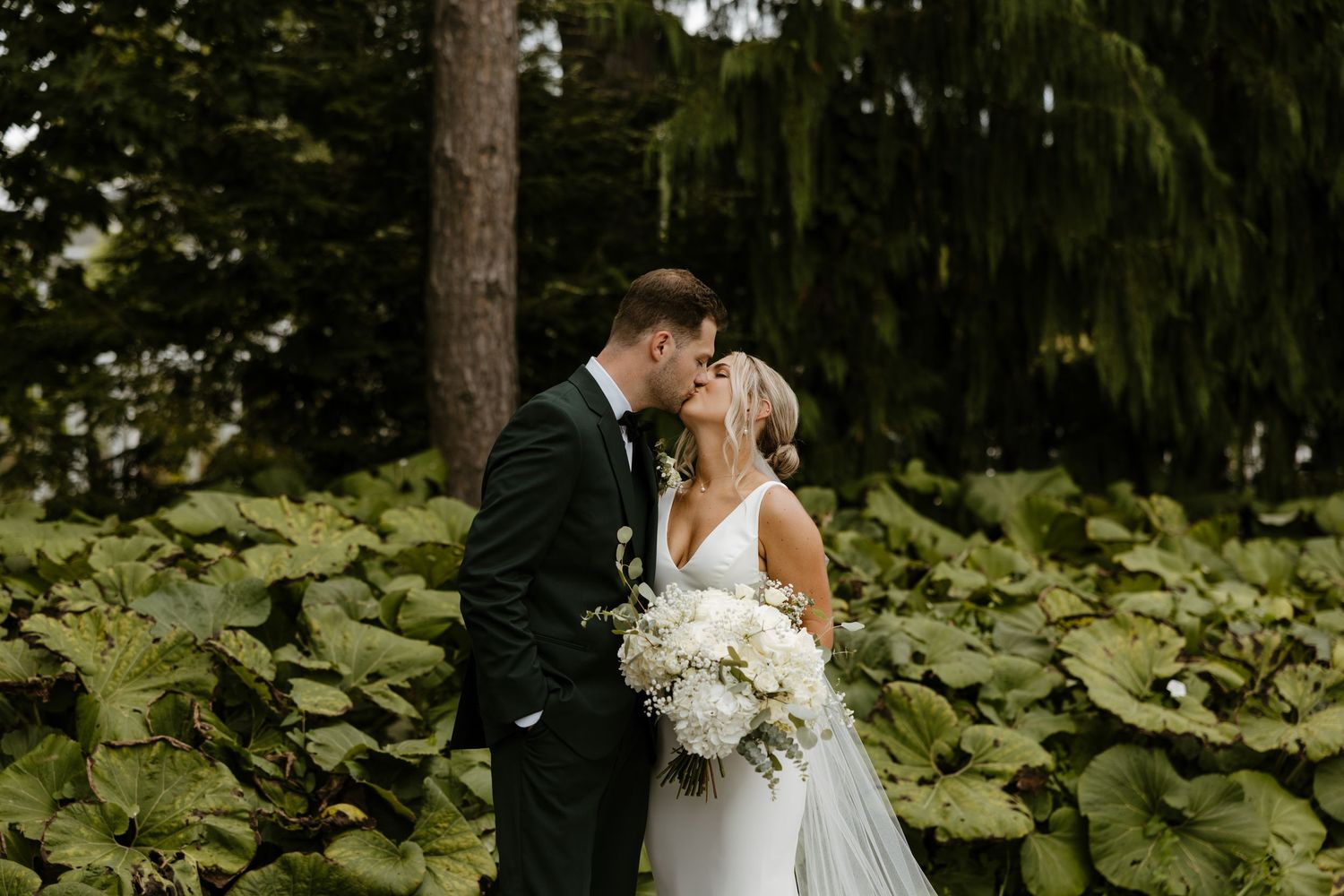 A bride and groom embrace in a lush, green garden setting. Fort Worth Texas wedding photographer.