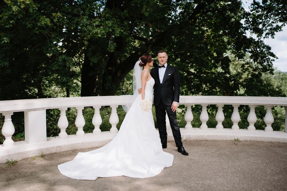 Couple poses on an elegant balcony with white stone balustrades during their wedding.
