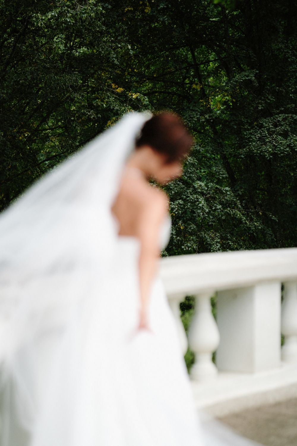 A flowing white wedding dress creates an elegant motion blur against a lush green garden backdrop.