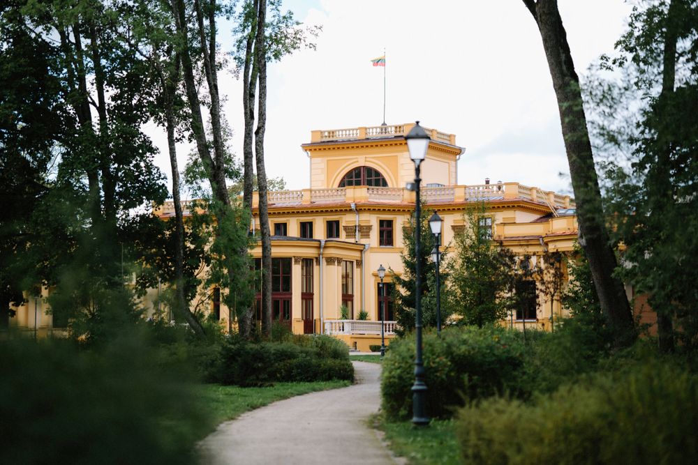 Mediterranean-style villa with terracotta roof visible through lush green trees.