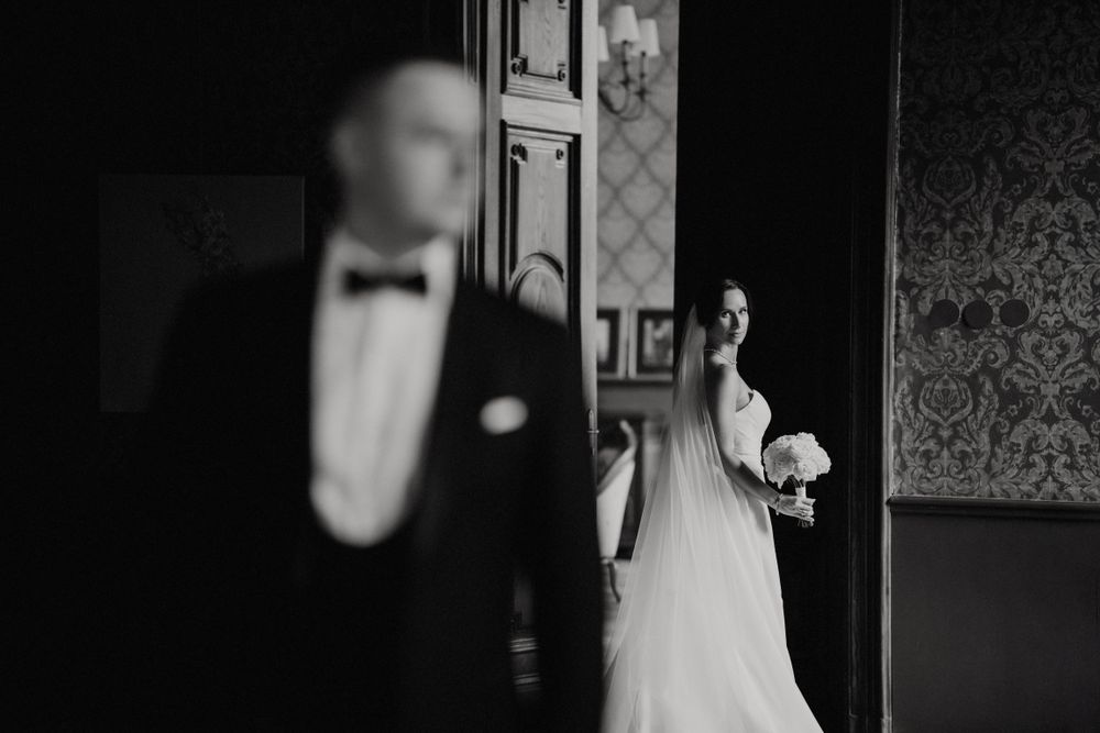 Dramatic black and white photo of a wedding couple in separate doorways.