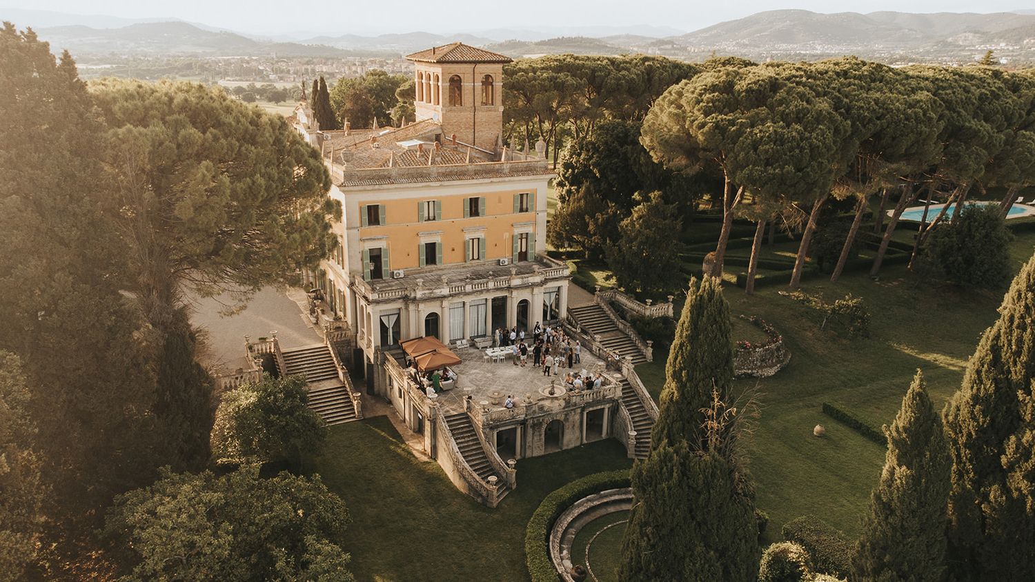 Drone image of Italian villa captured during golden hour with wedding guests on the outdoor terrace. Captured by Lincolnshire photographers.