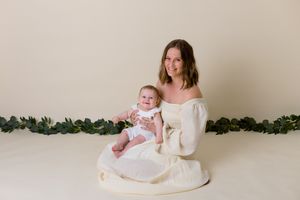 mom and daughter sitting in matching outfits on a cream background