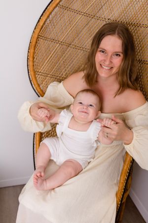 mom and daughter sitting on wicker chair with daughter looking up at mom