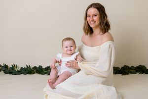 mom and daughter sitting in matching outfits on a cream background
