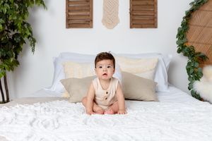 six month old boy sitting on bed