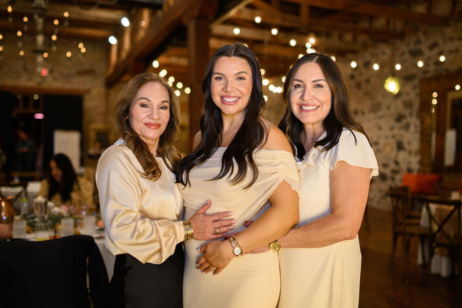 A grandmother and mom hug a mother-to-be at her baby shower hosted at the rustic Stone House & Co Event Venue in Twin Falls, Idaho.