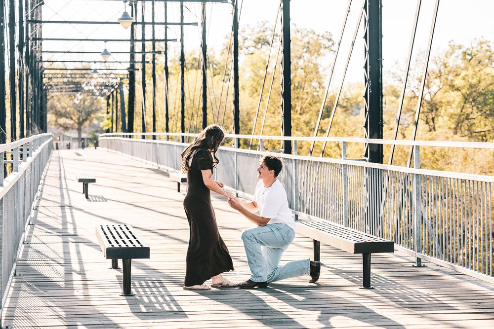 A couple shares a romantic moment on a modern pedestrian bridge during golden hour.