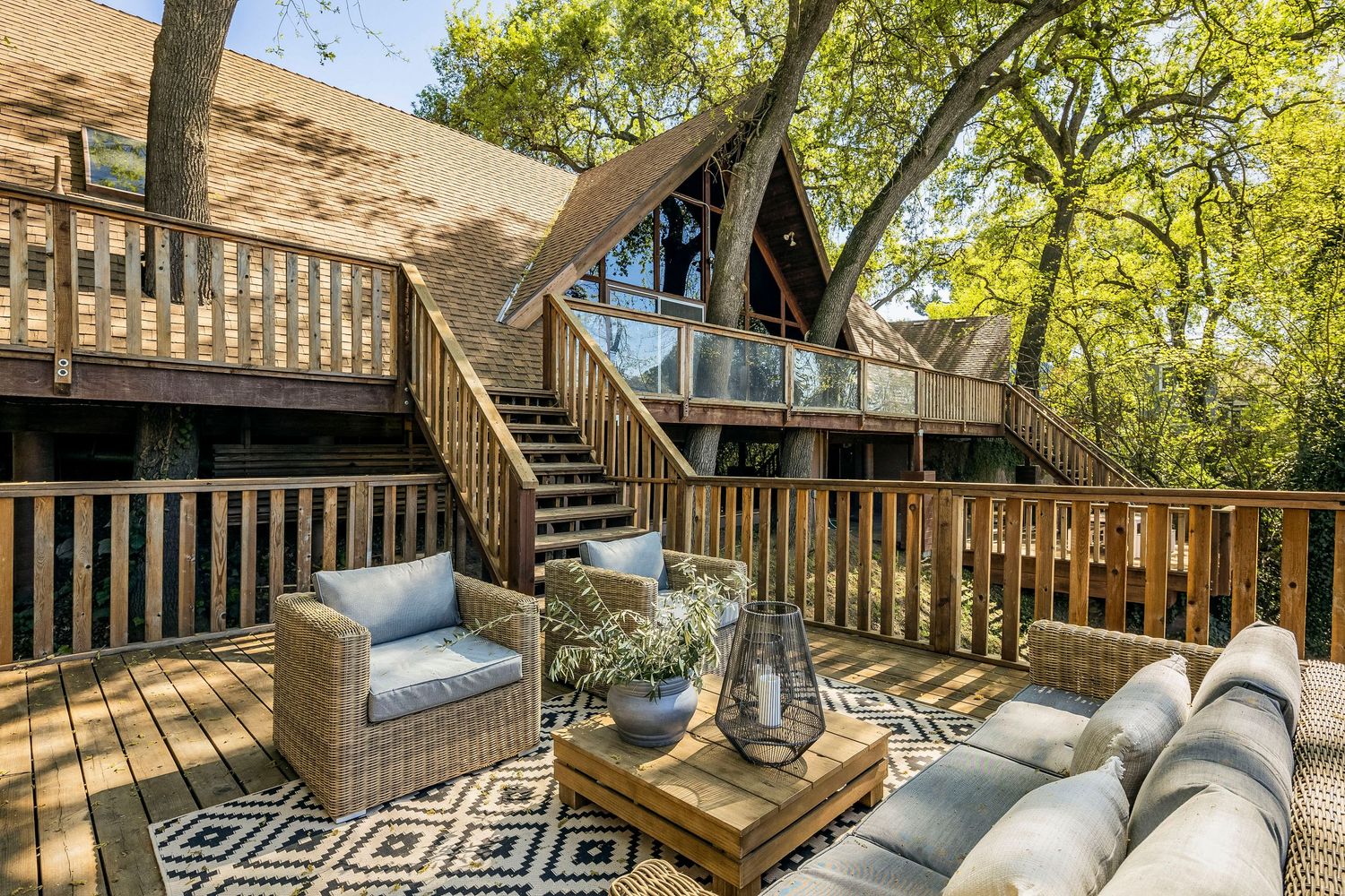 Modern rustic treehouse interior features wooden beams, spiral staircase, and geometric patterned decor in natural lighting.
