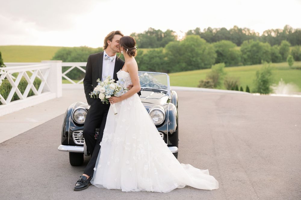 A couple shares an intimate moment on a white wooden bridge in a scenic outdoor setting.