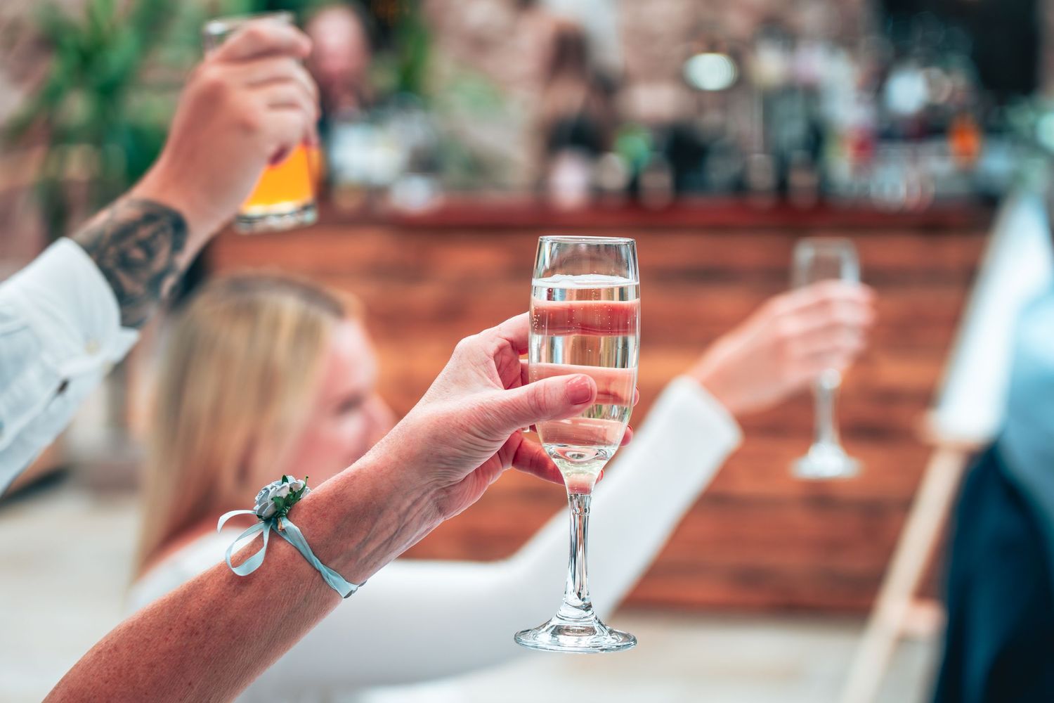 Guests raise champagne glasses in a celebratory toast at a wedding reception.