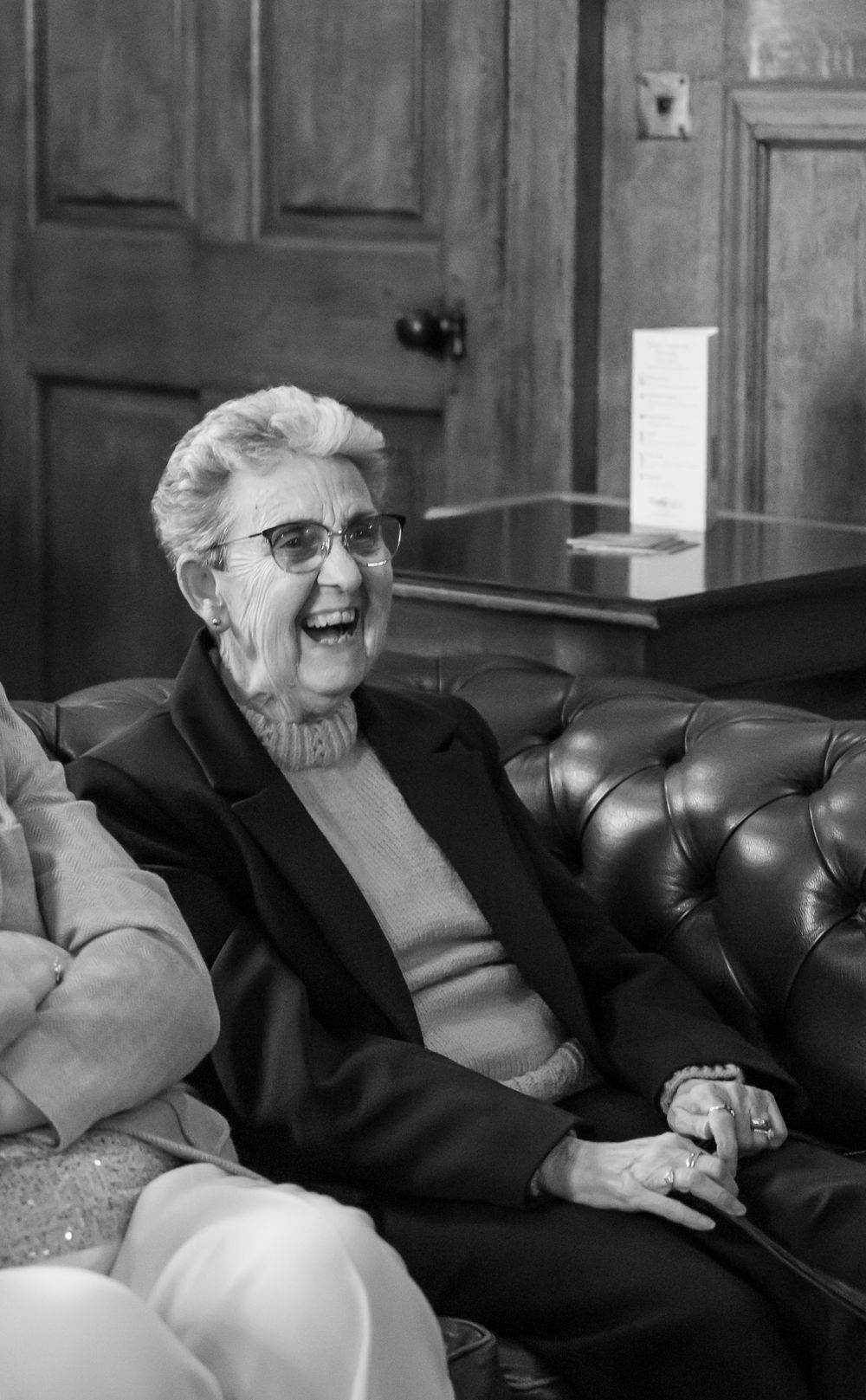Wortley Hall - A sequence of four black and white photos showing an elderly person in glasses laughing while reclining on a leather couch.
