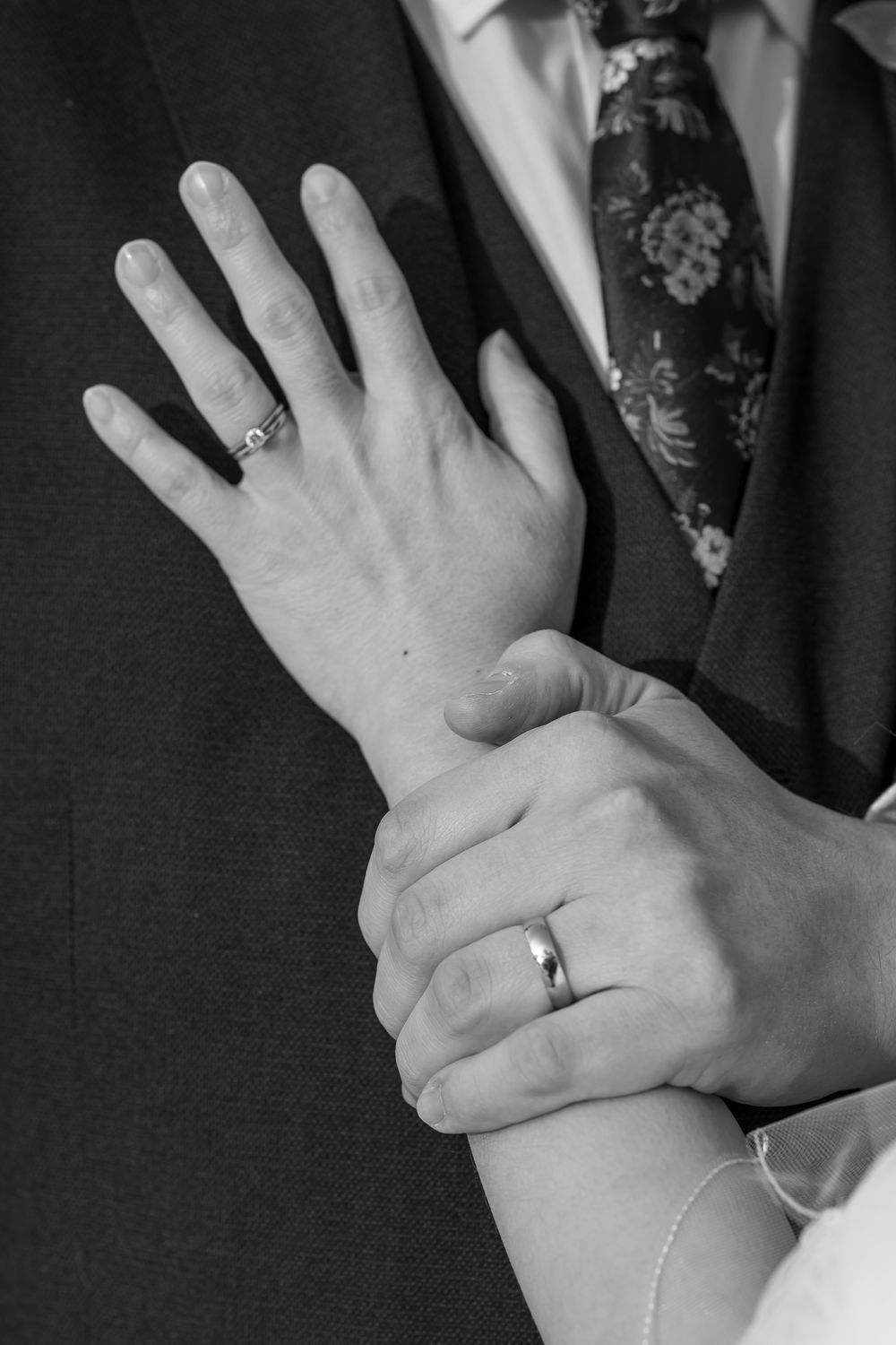 Whitley Hall - Close-up view of hands wearing wedding rings against dark formal attire showing elegant jewelry details.