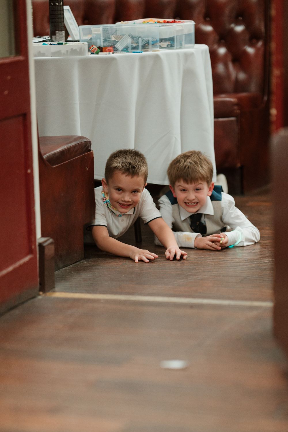 Wortley Hall - Two smiling children peek playfully from under a white tablecloth at a restaurant.