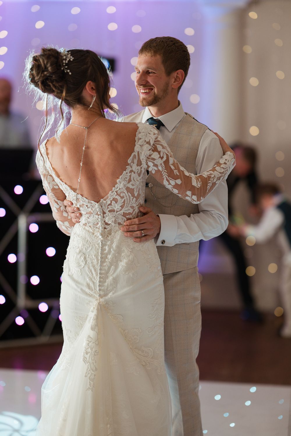 Wortley Hall - A bride and groom share their first dance at a wedding reception with twinkle lights in the background.
