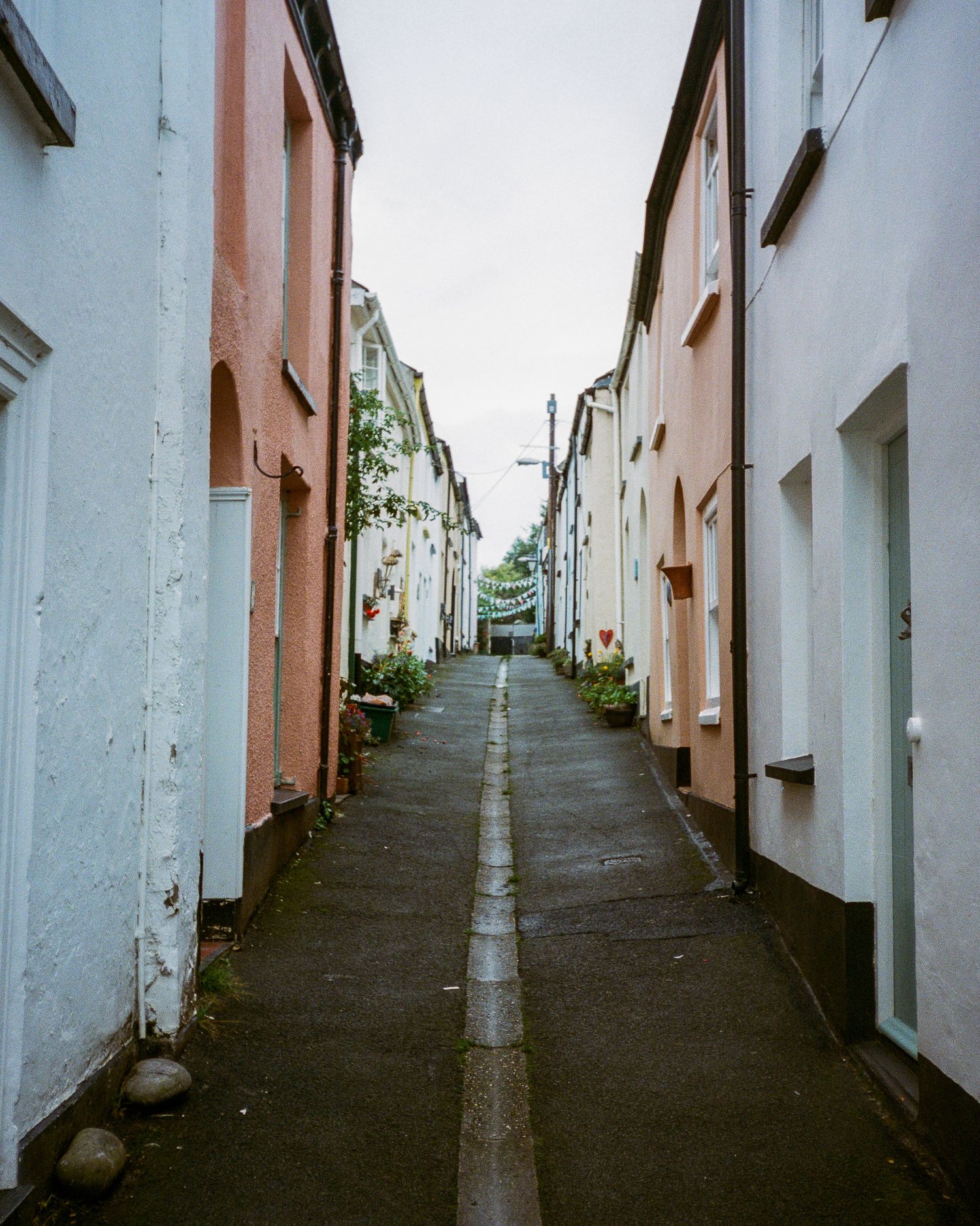 Narrow alleyway between white buildings leading uphill on a steep incline.