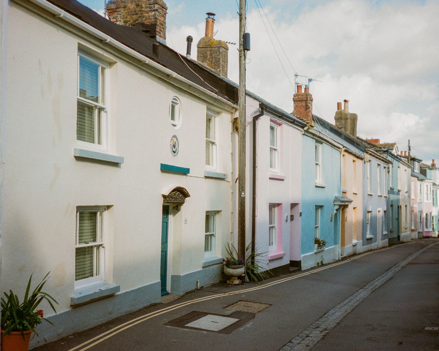Row of pastel-colored cottages along a seaside street with white and blue facades.