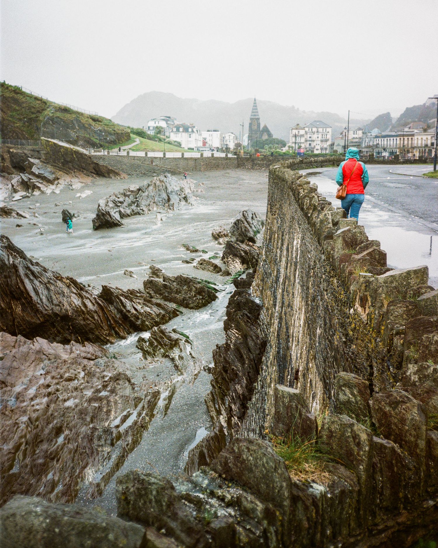 Rocky coastal cliffs with rough waves crashing against the shore on a cloudy day.