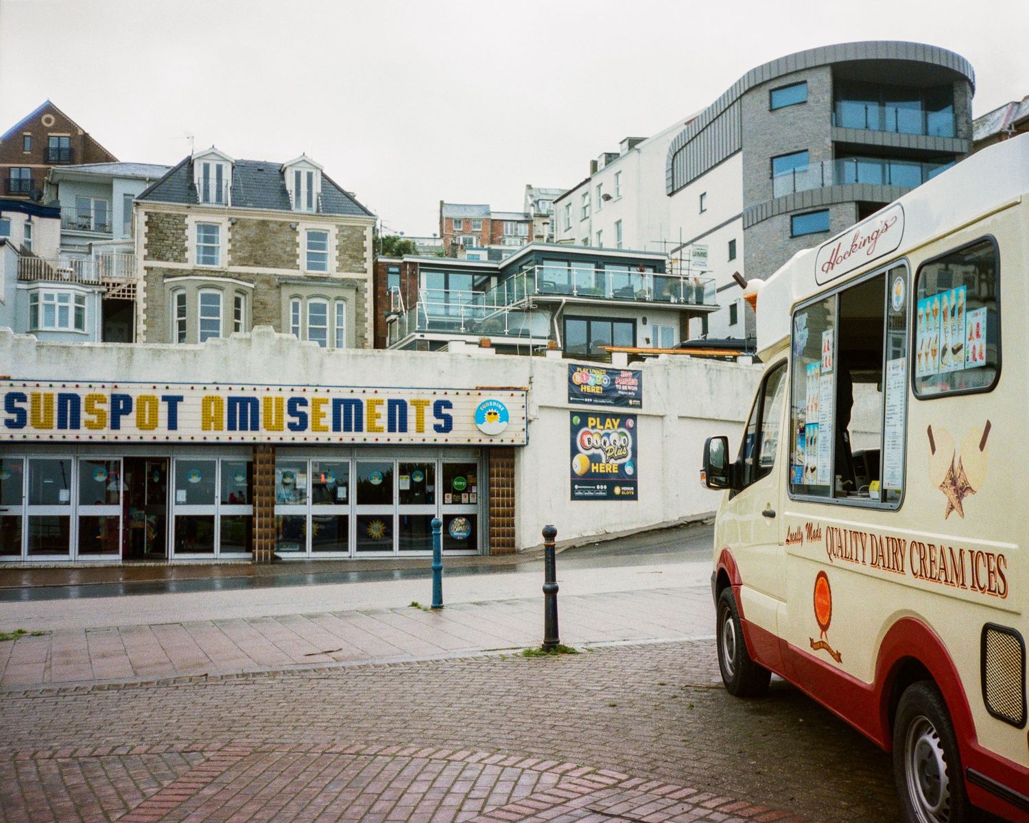 Vintage seaside amusement arcade and tourist shops with classic buses parked outside.