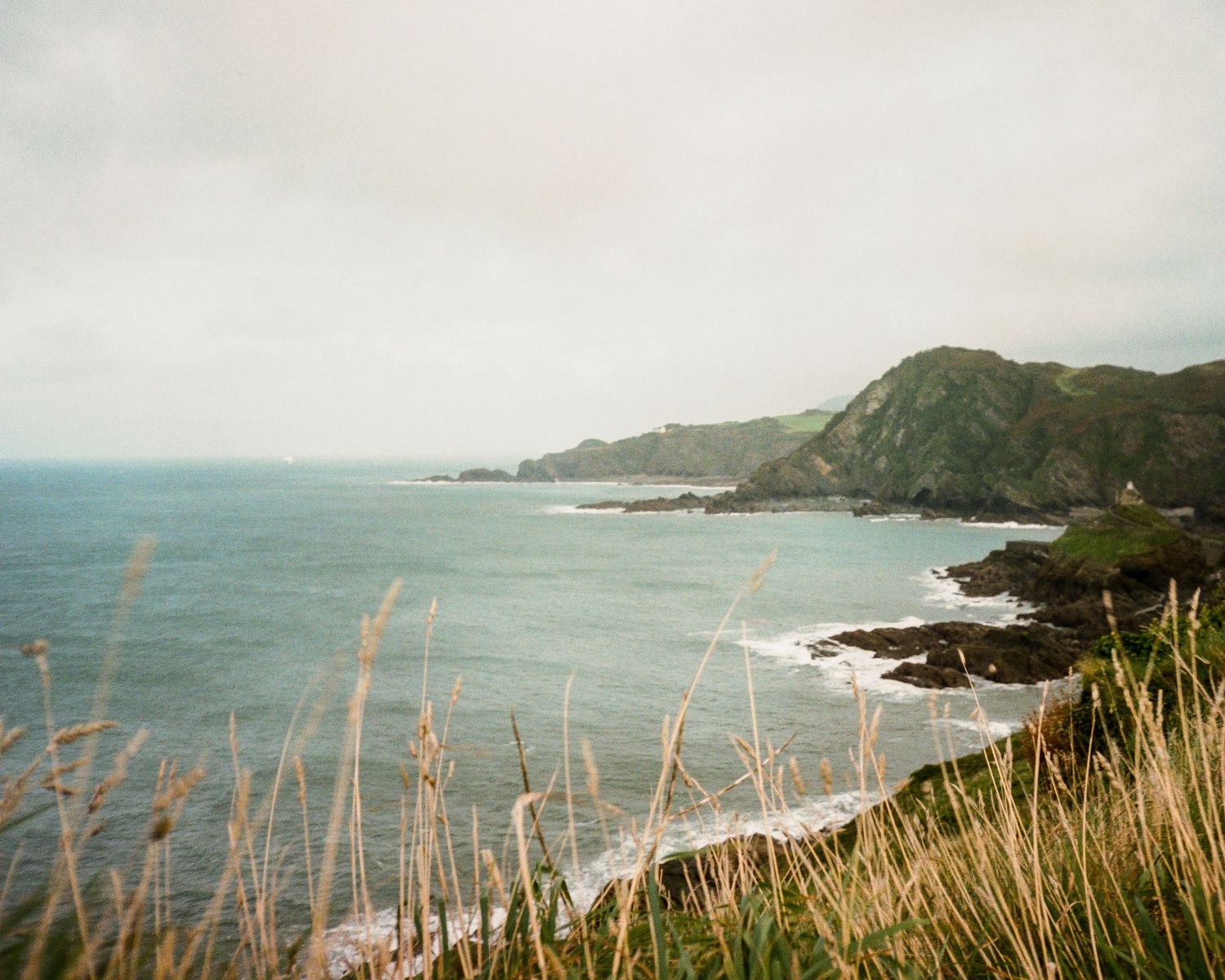 Dramatic coastal landscape with rugged cliffs and crashing waves along a scenic shoreline.