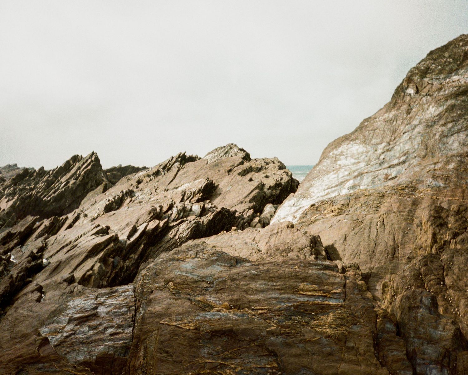 Textured rock formations with layered sedimentary patterns against an overcast sky.