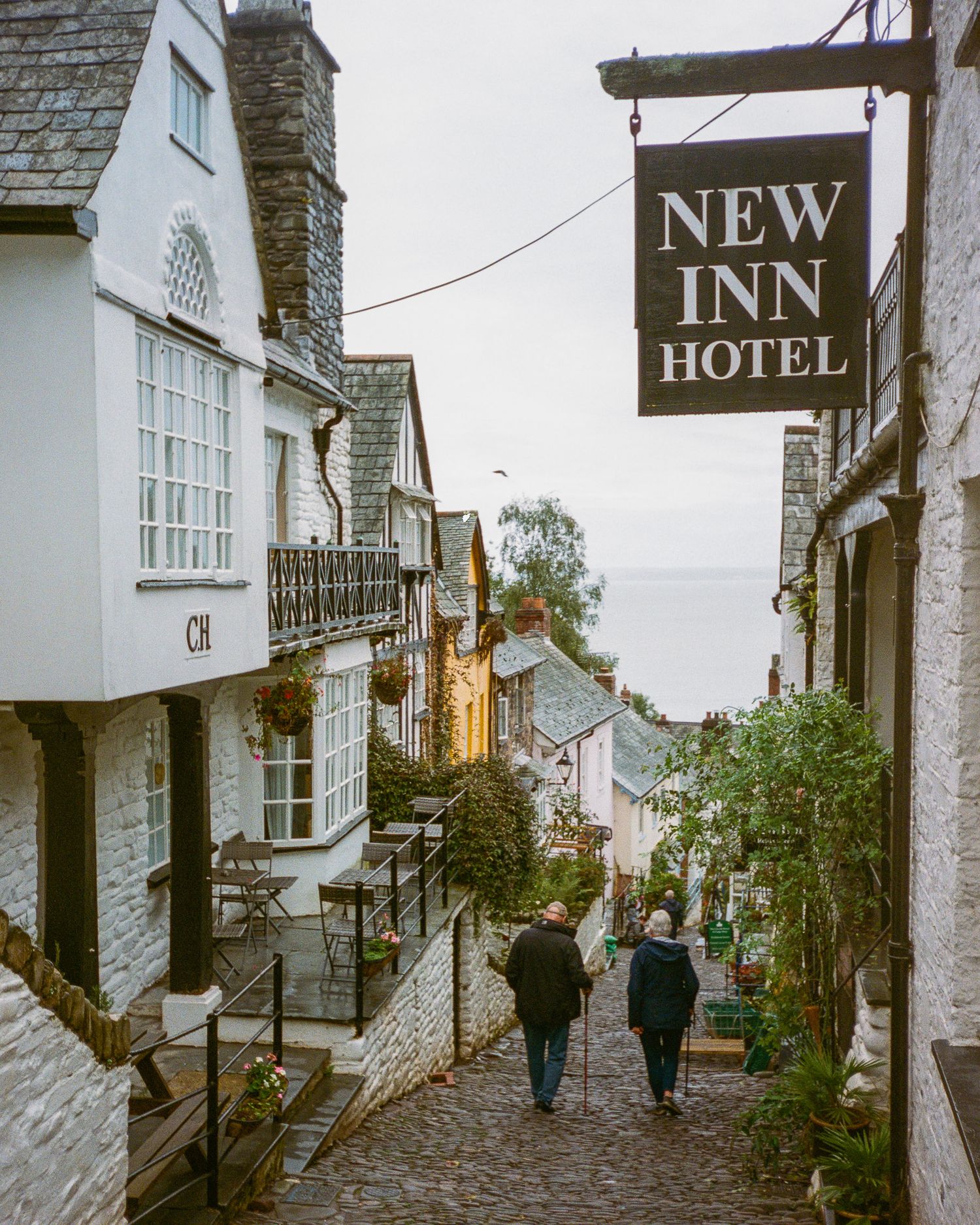 Charming cobblestone street in a historic village with white buildings and a New Inn hotel sign Clovelly.