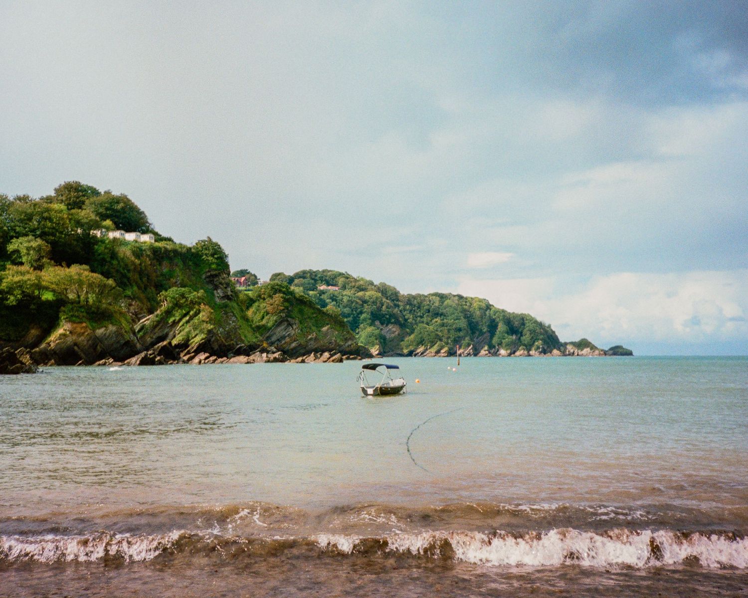 Scenic coastal bay with calm waters and green hills in the background.
