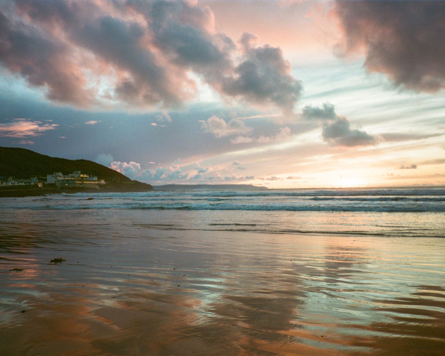Serene beach landscape at sunset with waves reflecting golden light. Westward Ho!