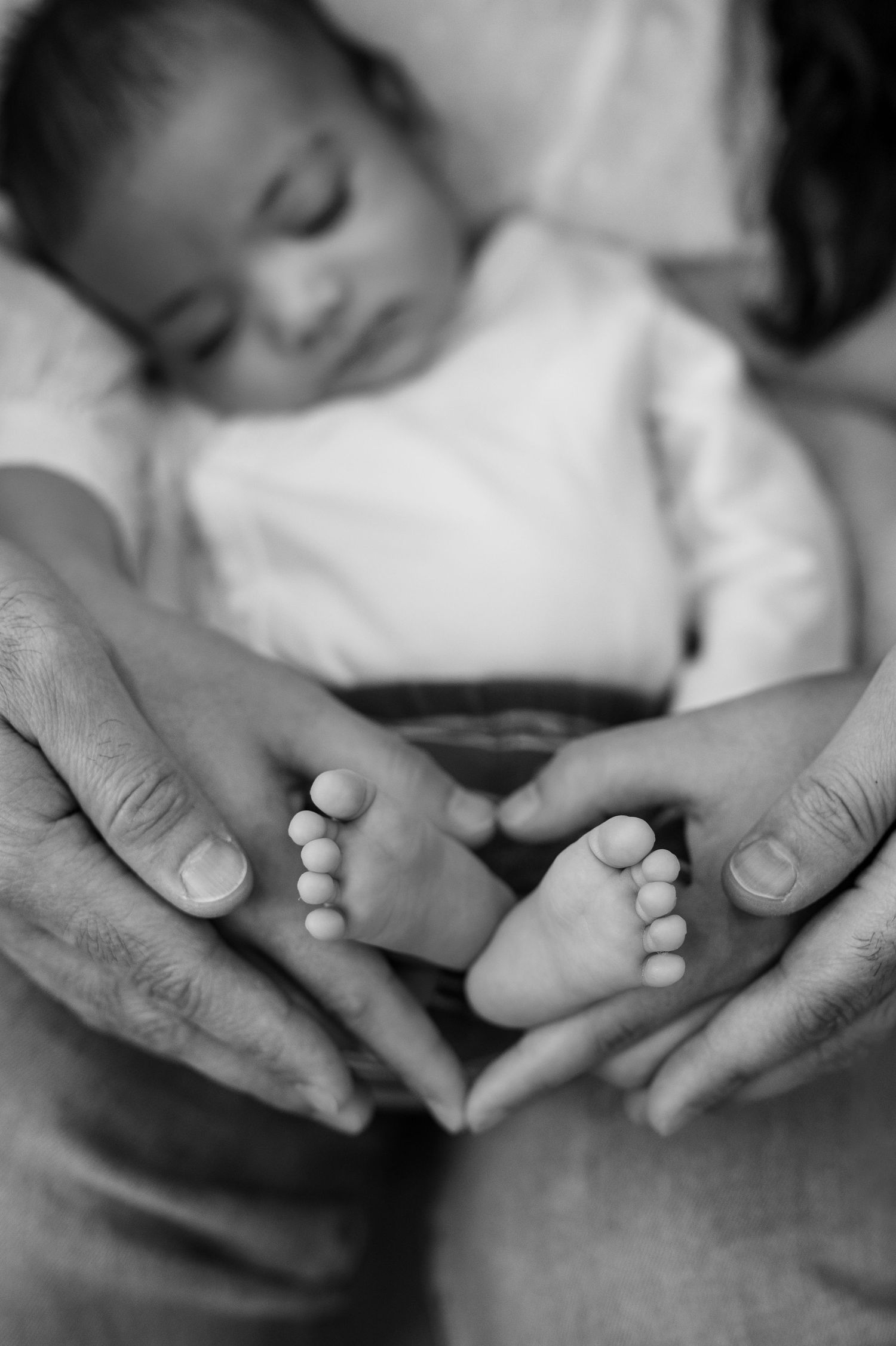 A black and white photo series showing gentle hands massaging and holding tiny baby feet in tender moments.