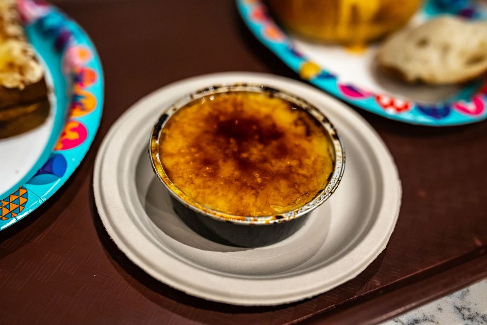 Freshly torched creme brulee desserts with caramelized sugar tops served on white plates at a restaurant.
