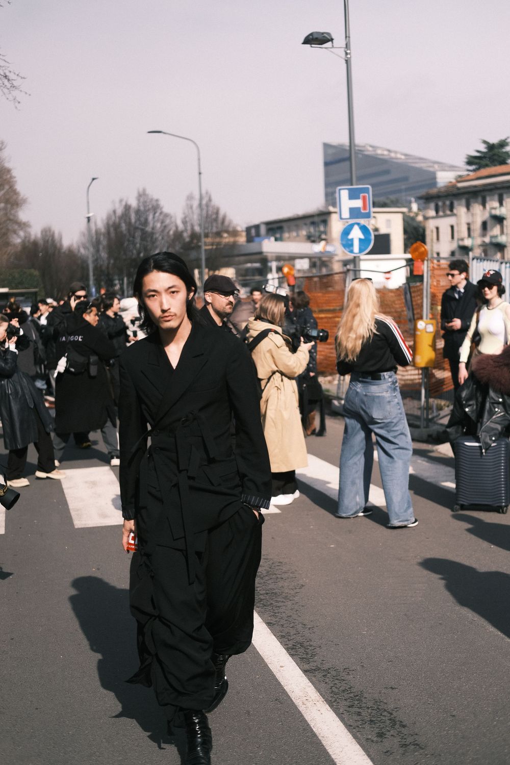 A sequence of street photos showing a person in black clothing walking along an urban sidewalk with other pedestrians.