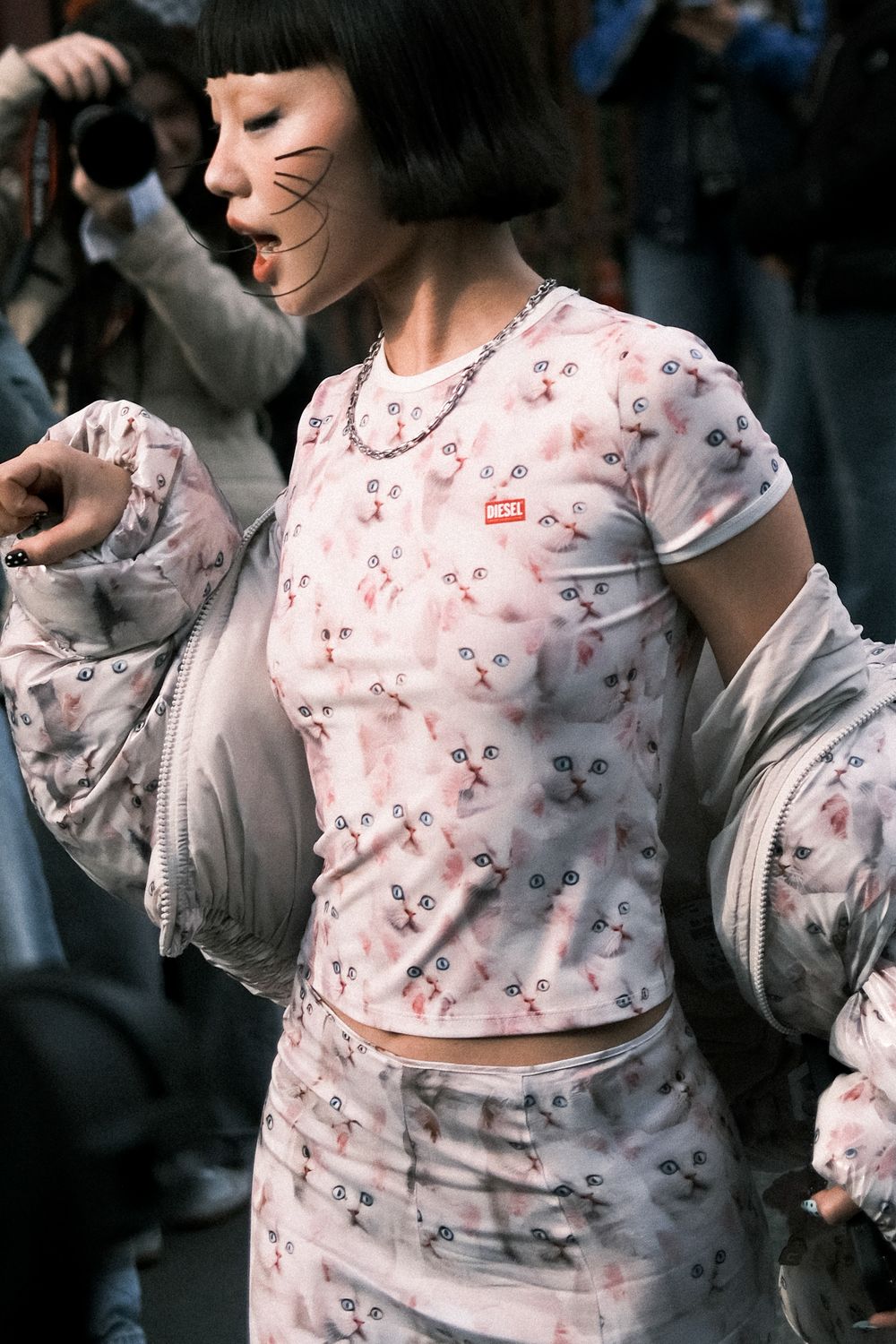 A person wearing a delicate white and pink floral patterned top dances gracefully in a dimly lit setting.