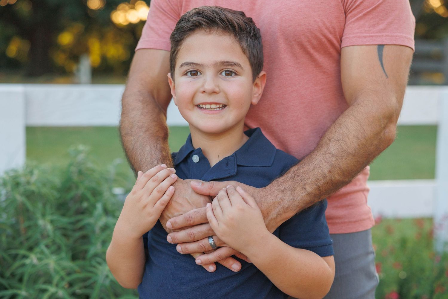 A parent and child share a tender moment outdoors during golden hour lighting.