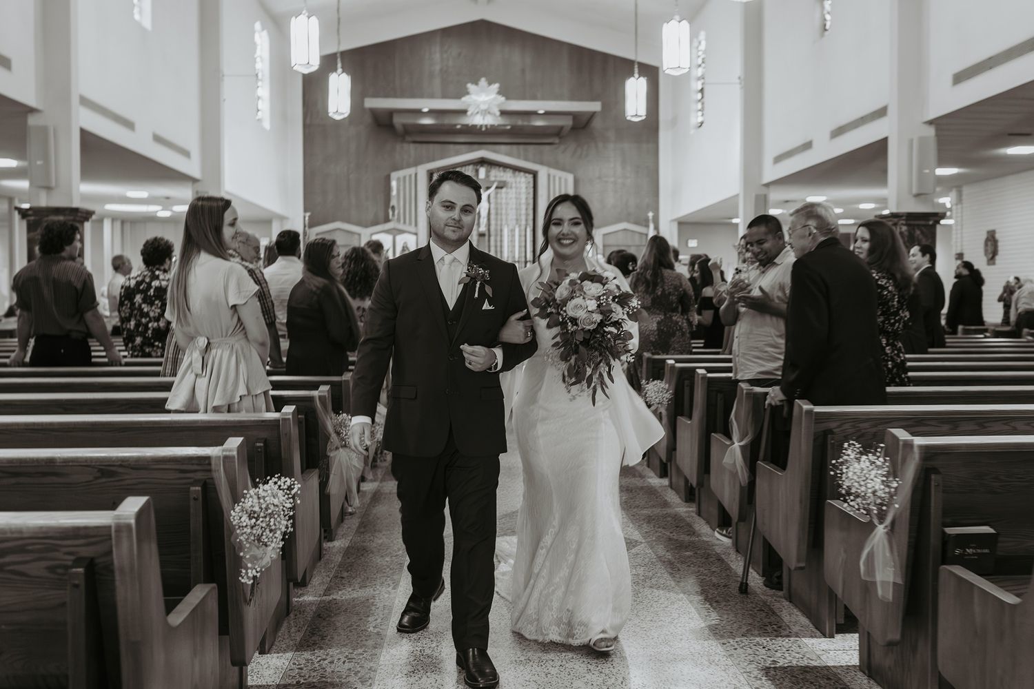 A black and white photo of a church wedding ceremony showing the couple walking down the center aisle in Escondido, California.