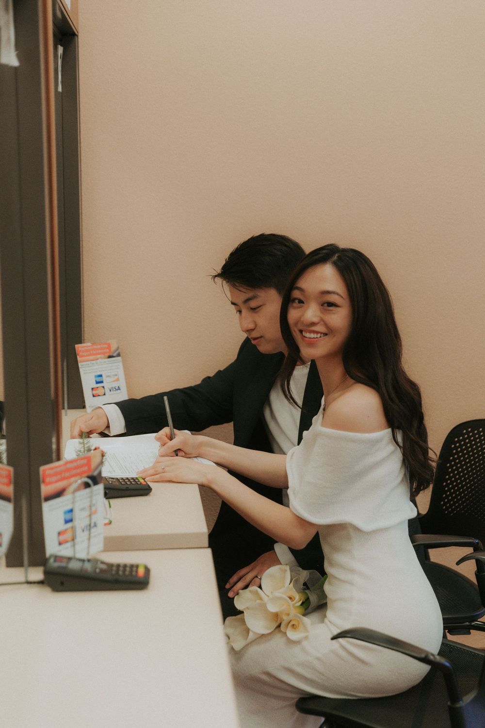 A couple shares a joyful moment while sitting together at a desk with papers and documents.