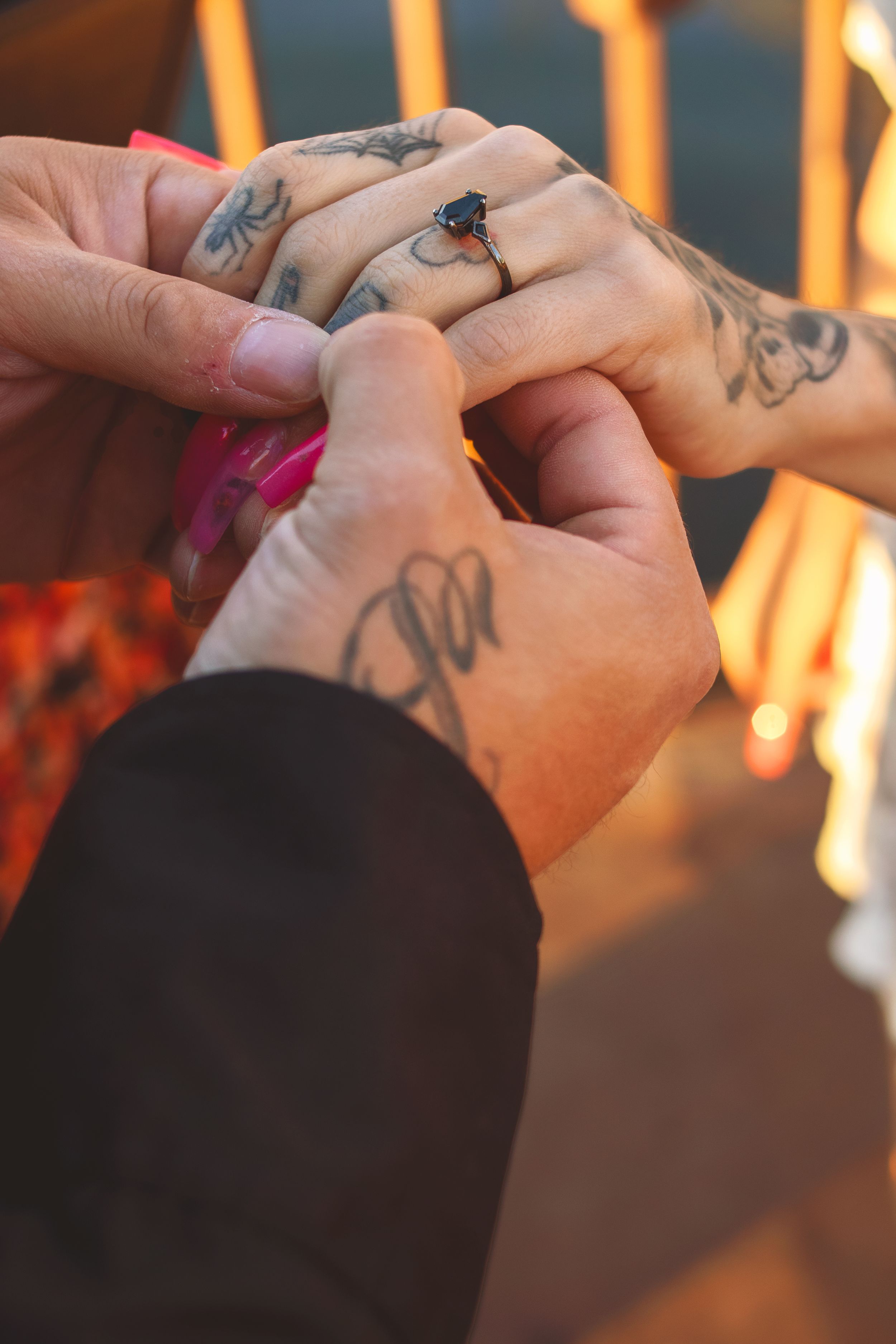 Close-up of hands with tattoos holding a ring in warm sunset lighting in Williston, North Dakota.