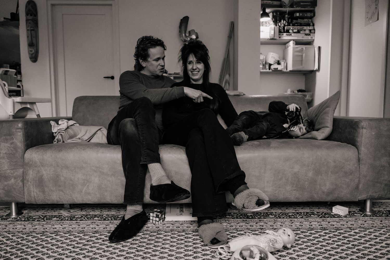 Couple relaxing on grey couch in black and white photograph.