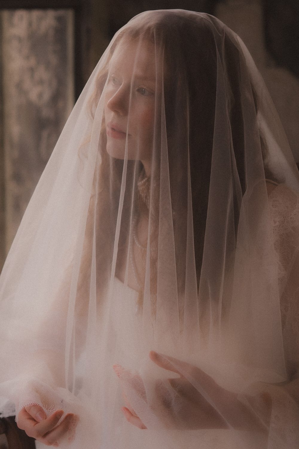 A bride wearing a delicate white veil is shown in a series of soft, romantic portraits with vintage-style lighting.