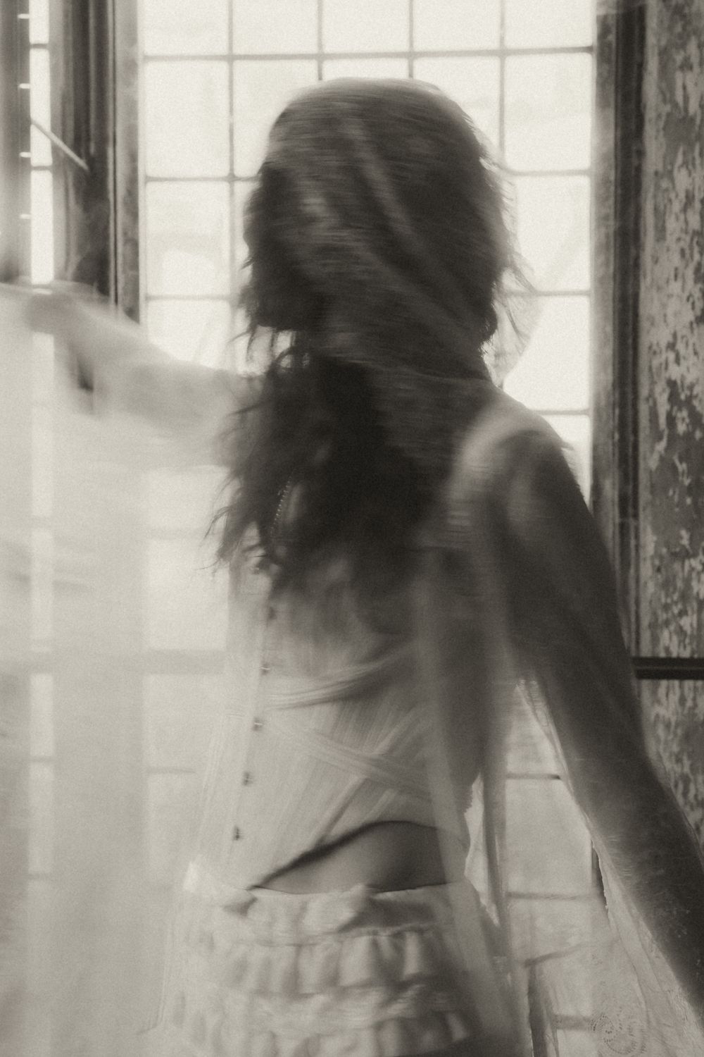 A black and white photo sequence shows a figure with long hair moving in a blurred, ethereal motion against a window.