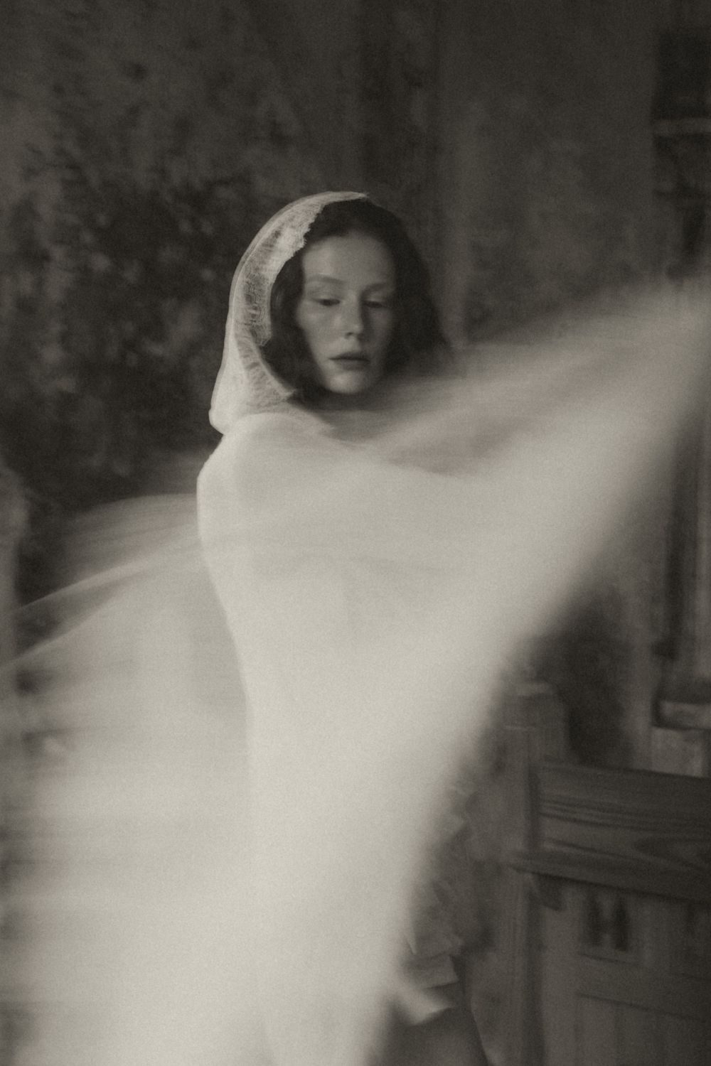 A ghostly figure in white appears to move through darkness in this vintage-style multiple exposure photograph.