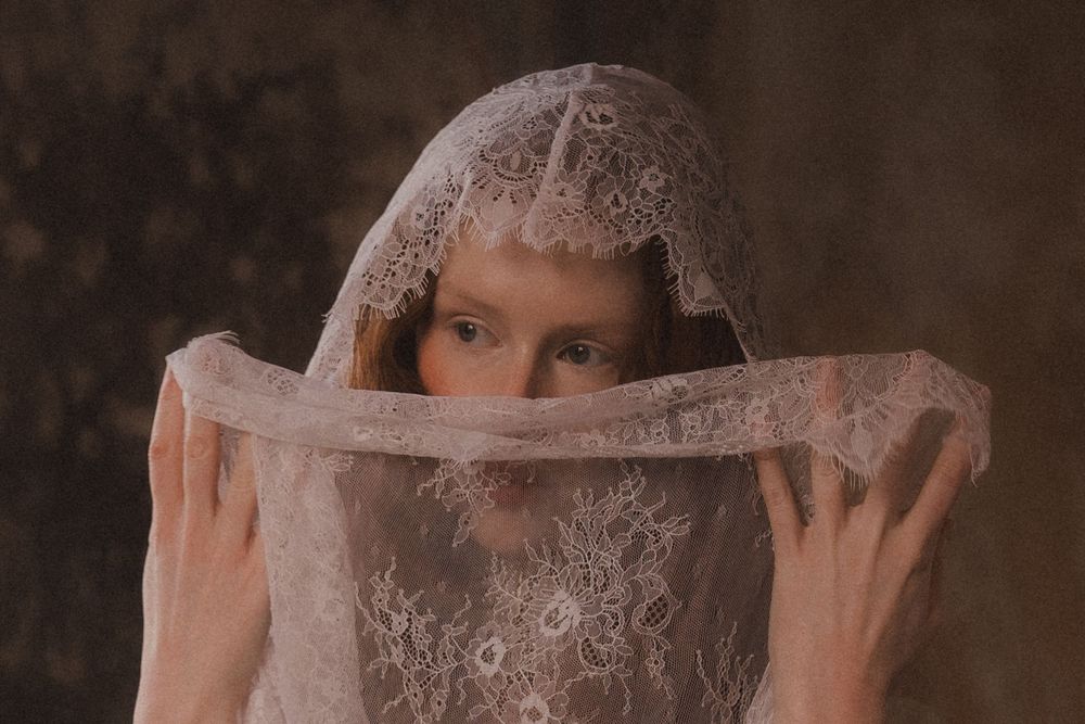 A dreamy portrait through sheer pink fabric creates an ethereal and romantic atmosphere.