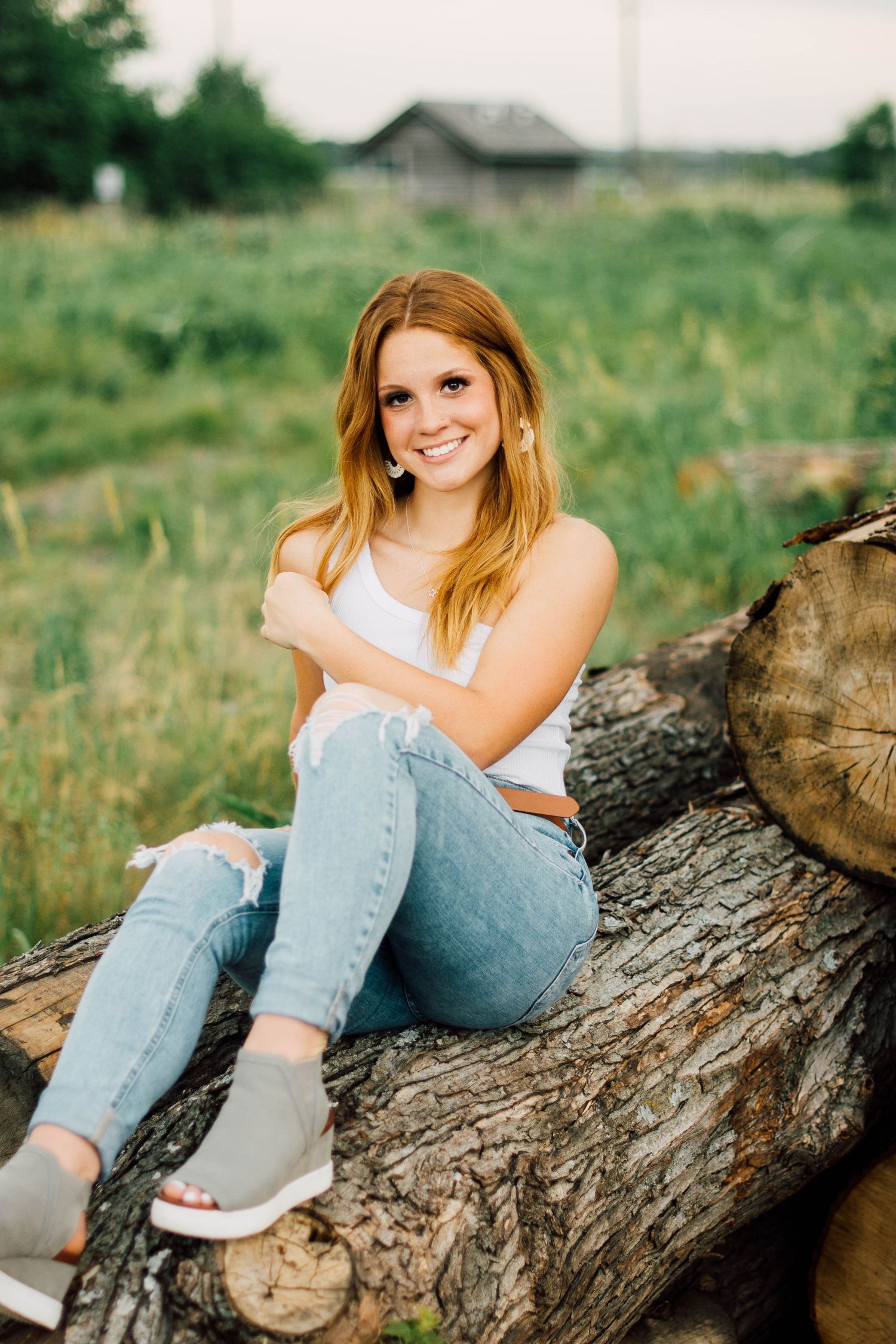 Casual portraits taken on a fallen log in a grassy field.